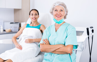 Portrait of professional mature beautician smiling confidently in medical esthetic office