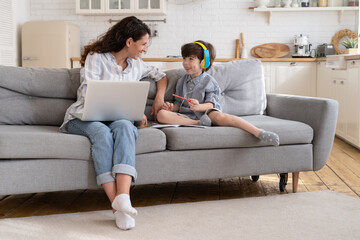 Mother freelancer enjoy helping little son with homework and distance lessons while working...