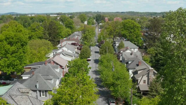 Aerial of quiet neighborhood establishing shot in summer. Daytime view of 1900s architecture homes.