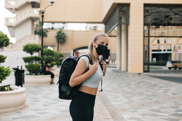 A young tourist girl in a face mask with a backpack is traveling during a vacation. Travel and tourism industry during the pandemic