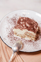 Traditional Tiramisu Cake served on a white plate over wooden background. Italian French cuisine concept