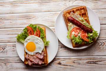 Waffle wholesome breakfast. Sour waffles with grilled sausages, fried eggs, delicious sauce and fresh vegetables.