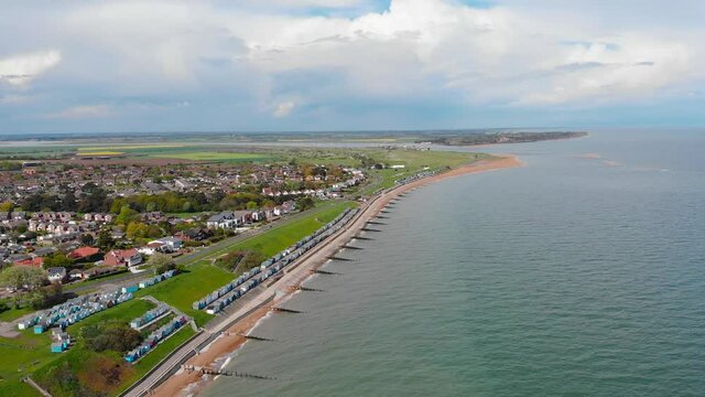 Coastal town of Lowestoft in the county of Suffolk, England; a revealing aerial footage of a beachfront, town and coastal roads, a lovely scenic horizon with clouds and landscape including the sea.
