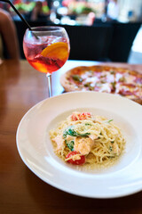 Italian food at restaurant table - Pizza, aperol spritz, and plate of pasta