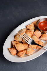 Fried dumplings stuffed with meat and served with tomato sauce on a white plate.