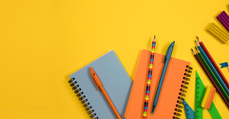 School background. Stationery scattered on a yellow background. Notebooks and pens on a yellow background. Close-up, flat lay, horizontal, top view, copy space. Education concept.