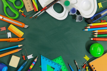 School background. Copy space on the green school board in the center of the frame. Stationery is scattered around. Close-up, flat lay, horizontal. Education concept.