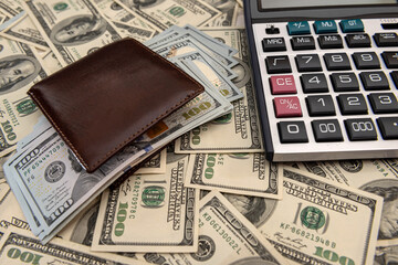 us dollars bills in the wallet with calculator