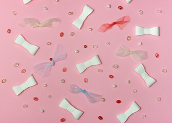 Pink paper background with paper and fabric ribbons and beads.