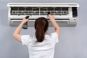 woman cleaning the air conditioner indoors at home
