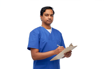 healthcare, profession and medicine concept - indian doctor or male nurse in blue uniform writing...
