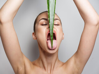 woman with aloe leaf over her head and clean skin cosmetology wide open mouth model