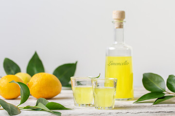 Limoncello - italian lemon liqueur, fresh italian lemons. Light background, copy space.