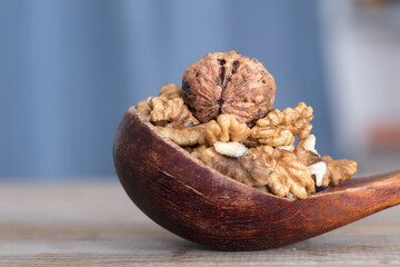 Dried walnuts and walnut kernels in a wooden spoon