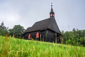 A wooden church on top of Mala Prasiva in Beskydy mountains during a cloudy day.