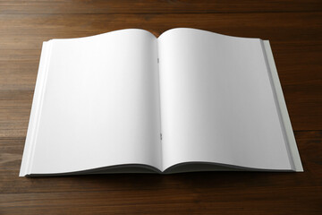 Open blank paper brochure on wooden table. Mockup for design