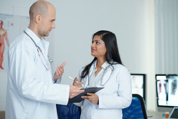 Physicians standing in medical office and discussing symptoms and possible diagnosis of patient