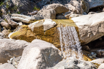 Water flowing down in a stream full of stones in the Swiss alps