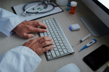 Hands of physician working on computer after making rounds and examining patients in the morning