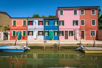 Fototapeta na wymiar Burano island in the Venetian lagoon with small multi colored houses (bright colors) and a canal with moored boats in a sunny spring day. Venice, UNESCO world heritage site, Veneto, Italy, Europe.