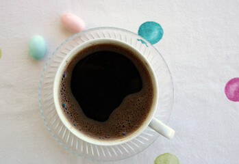 cup of dark coffee with candy on the table, top view