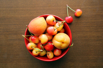 Naklejka na ściany i meble Cherries and apricots fresh summer fruits in the bowl, top view