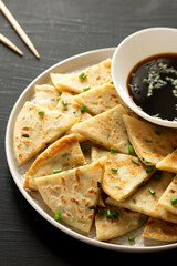 Homemade Scallion Pancakes with Soy Dipping Sauce on a black background, side view.