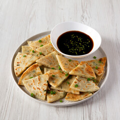 Homemade Scallion Pancakes with Soy Dipping Sauce on a white wooden background, low angle view.