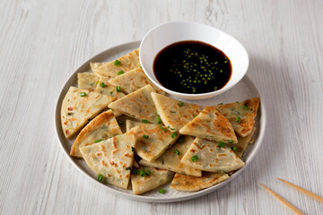 Homemade Scallion Pancakes with Soy Dipping Sauce on a white wooden background, side view.
