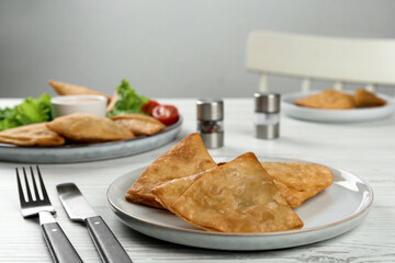 Fresh delicious crispy samosas served on white  wooden table
