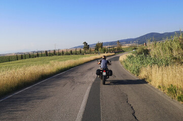 Fototapeta premium motociclista su strada di campagna guida la sua moto da turismo