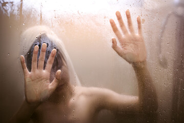 Scared girl hand behind glass door with lens flares