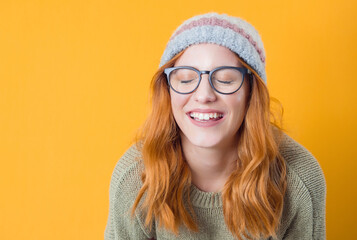 Closeup laughing young woman with eyes closed, isolated on yellow background. Beautiful female person with laugh expression