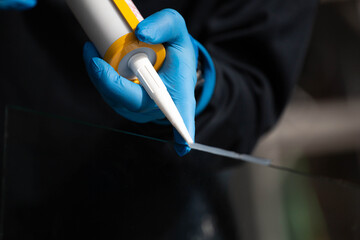 Fototapeta na wymiar Closeup of silicone glue and a glue gun to tightly stretch aluminum and glass.