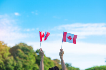 hand holding Canada flag on blue sky background. Canada Day  and happy celebration concepts