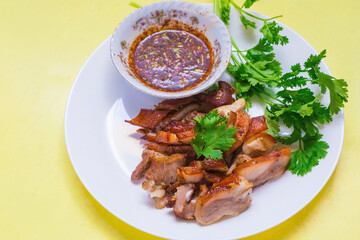 Grilled pork mask was marinated with minced coriander root, black pepper and garlic and served with Thai spicy sauce (Jaew sauce).