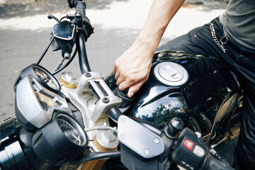 Close-up image of man opening motorcycle oil tank to fill ot with gasoline
