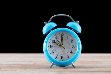 An alarm clock in front of a black background
