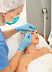Portrait of woman during beauty facial injections in medical esthetic office. High quality photo