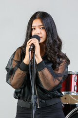 Portrait shot of teenage singer singing a song with a microphone while looking at the camera. Happy...