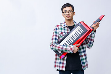 Portrait shot of handsome young teenage musician playing the keytar while looking at the camera in...