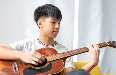 Close-up shot of young male musician playing the acoustic guitar. Selective focus on the...