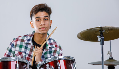 Close-up portrait shot of a teenage drummer playing the music. Selective focus at the drum with a...