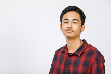 Vertical front-view portrait shot of a handsome young male teenager wearing trendy long sleeve clothes looking at camera in the studio isolated with a white background.