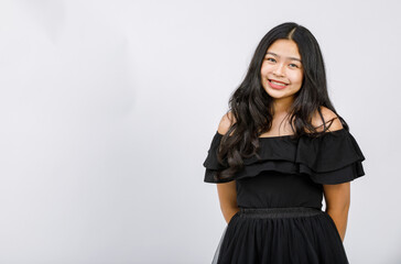Horizontal half-body portrait shot of a beautiful smiling young girl teenager in a black dress looking at camera in the studio isolated with white background. There is copy space on the side of image
