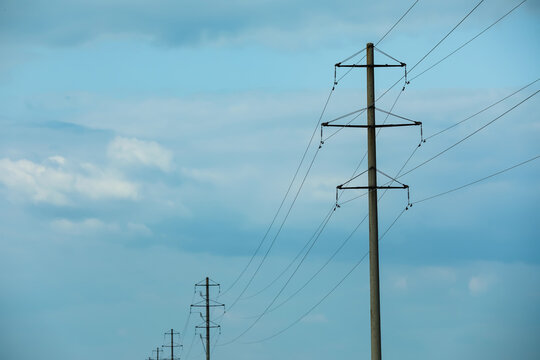 Telephone poles and wires against blue sky with clouds