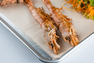 Set of seafood with large grilled shrimps on metal plate with carrot, lettuce close-up.