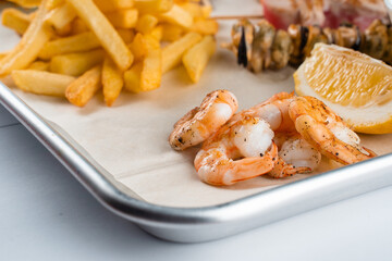 Set of seafood with grilled shrimps on metal plate with carrot, lettuce close-up.