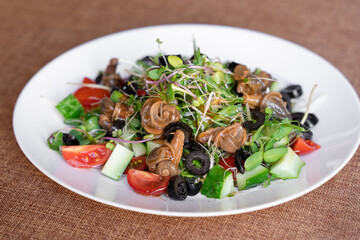 Salad with snail, olive, tomatoe cherie, cucumber and greens