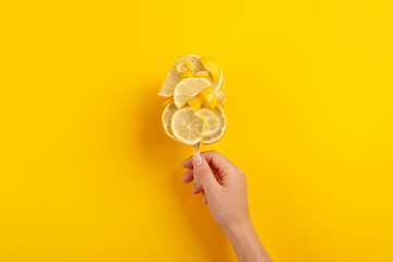 Fototapeta na wymiar Creative ice cream made from lemon in female hand. Refreshing bright summer dessert on yellow background 